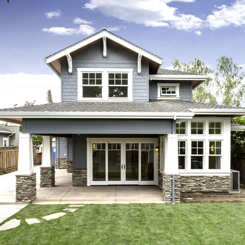 Blue-gray custom home with white highlights, stone veneer and green lawn.