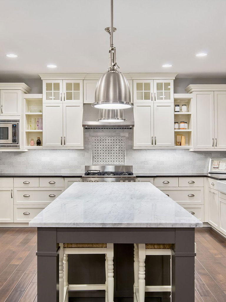 White kitchen in a custom home with tile backsplash, chrome detailing and marble counter tops.