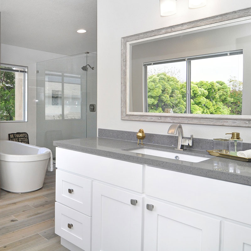 White bathroom with gray countertop and freestanding bathtub.