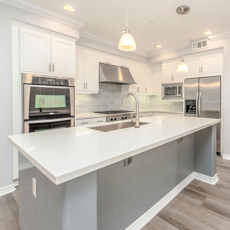 White custom kitchen with white marble countertop and chrome accents.