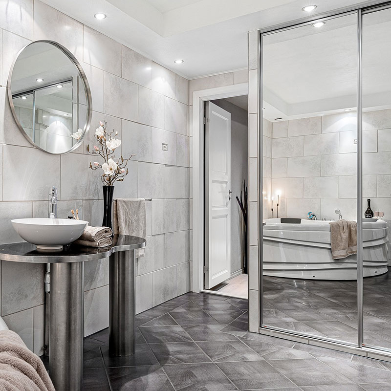 Stone tile bathroom in white and gray, with a floor-to-ceiling mirror and modern appliances.